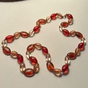Long beaded necklace with clear and burnt orange plastic beads